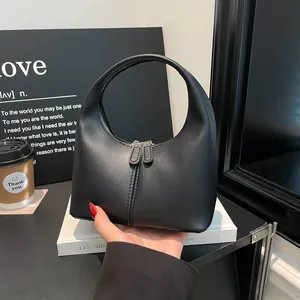 Minimalist black matte leather handbag with curved handle and dual zipper closure