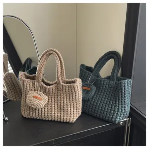 Detail von handgefertigten Stricktaschen in Haferflocken und Blaugrün mit Anhängern