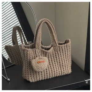 Detail der handgestrickten beige Woll-Tasche mit Textur und Hand Made Lederetikett-Anhänger