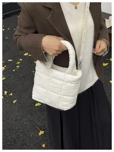 Close-up of a cream white quilted puffer tote bag with a detachable shoulder strap