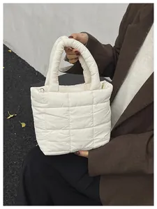 Detailed shot of white quilted puffer tote bag with padded handles and metallic rings
