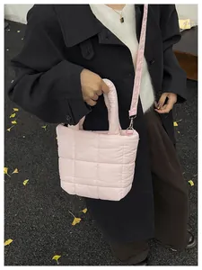 Pink quilted nylon puffer bag styled over a black coat with a detachable shoulder strap