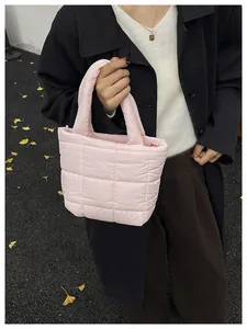 Detail of pink puffy quilted tote bag showing soft texture and padded handle on model