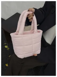 Detail of light pink quilted nylon puffer tote bag showing padded texture and handle