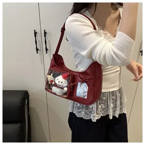 Detail of red Ita Bag with clear PVC window and plush toy insert on white knit sweater