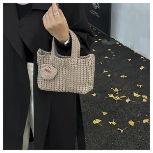 Detail der beige gestrickten Handtasche mit Herzanhänger und handgefertigtem Lederlabel