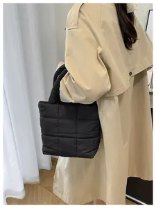 Fashionable black quilted tote bag shown on model for stylish shoulder carrying
