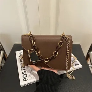 Brown faux leather crossbody bag with dual chains and gold metal geometric buckle