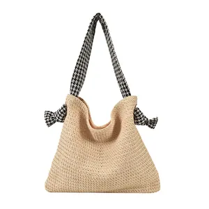 Large beige woven straw tote bag with houndstooth patterned shoulder strap and bows
