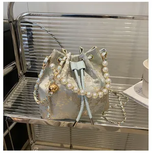 Detail of light blue jacquard bucket bag with pearl handle and golden ball charm