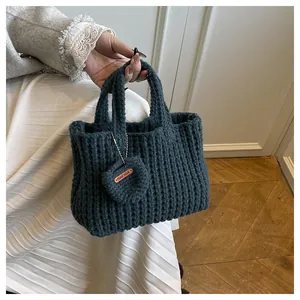 Nahaufnahme der dunkelgrünen Stricktasche mit vertikalen Streifen und Herz-Anhänger