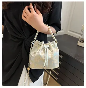 Detail of floral bucket bag with pearl handle, drawstring closure and chain strap
