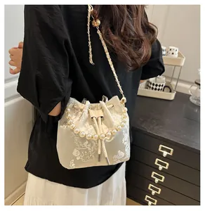 Detail of off-white floral bucket bag with pearl handle and golden chain strap