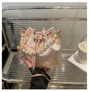 Detail of pink embroidered bucket bag with pearl handle and floral satin texture