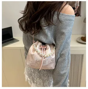 Detail of pink satin bucket bag with floral embroidery and elegant pearl handle