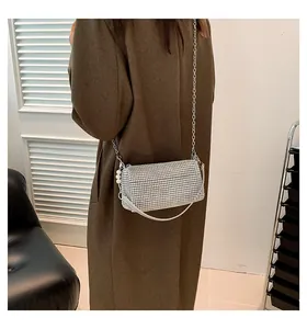 Detail of silver rhinestone shoulder bag with metal chain and pearl charm on a model