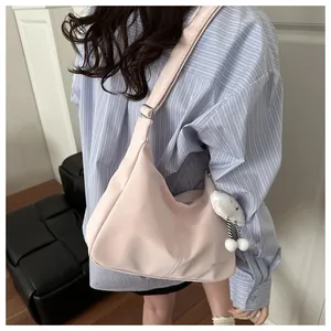 Detail of light pink waterproof nylon tote bag with plush cloud charm and adjustable strap