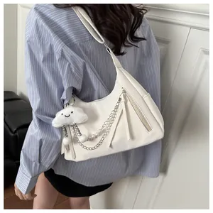 Close-up of a white hobo bag with silver chain and cute cloud plush charm on a model