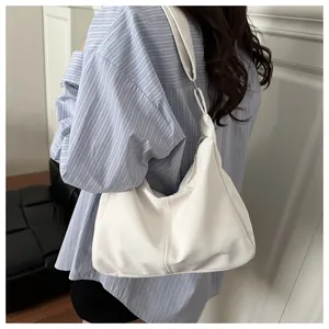 Detail view of a white crescent shoulder bag featuring a wide strap and brand logo