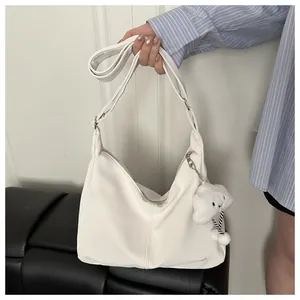 Detail view of white PU leather hobo bag with wide adjustable strap and plush charm