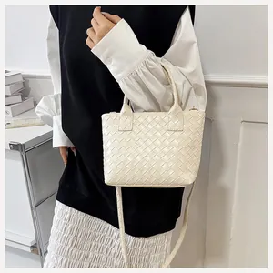 Detail of cream woven handbag showing crossbody strap and intricate texture