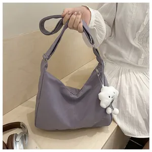 Detail showing a purple hobo bag with a plush cloud charm and adjustable strap