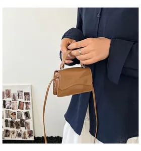 Gros plan d'un mini sac carré marron brillant avec rabat ondulé et fine bandoulière