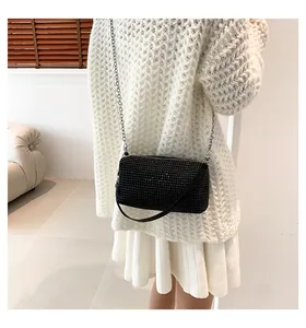 Detailed close-up of a black rhinestone mini evening bag with a silver chain strap