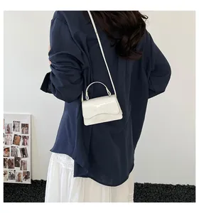 Vue arrière d'un sac à main blanc en cuir verni porté avec une chemise bleue et une jupe