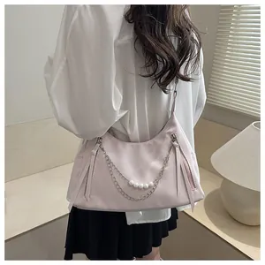 Detail shot of light pink shoulder bag with pearl chain accessory and silver hardware