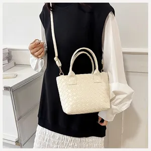 Detailed view of cream woven texture handbag with adjustable shoulder strap on model