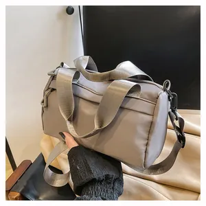 Detalle de bolso bandolera de nailon gris con correa ancha y hebilla de plástico
