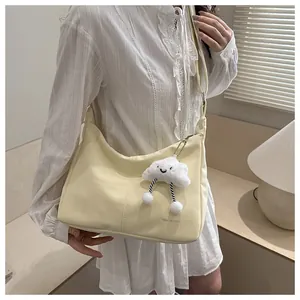 Detail of soft cream yellow PU leather shoulder bag with plush cloud charm and logo