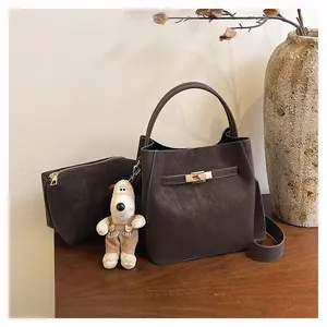 Detail der dunkelbraunen Leder-Eimertasche mit Metallschloss und Plüschhund