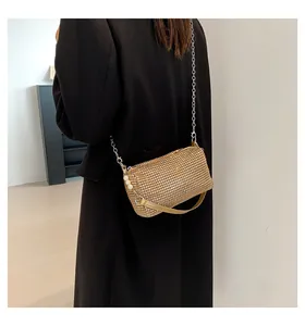 Detail of a gold rhinestone purse with pearl accents and a chain strap on a shoulder