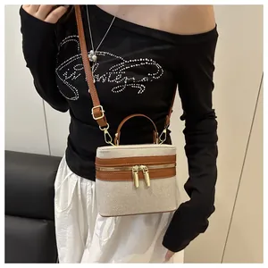 Close-up of color-block canvas box bag with brown leather trim and golden zipper