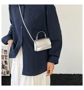 Mini sac argenté sur mannequin avec finition miroir et rabat découpé en vagues