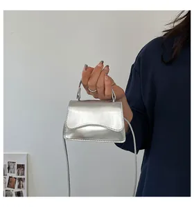 Détail d'un mini sac à main argenté miroir avec rabat festonné et fine bandoulière