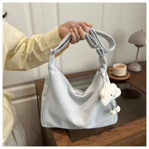 Detail of light blue crescent hobo bag with a soft plush white cloud keychain accessory