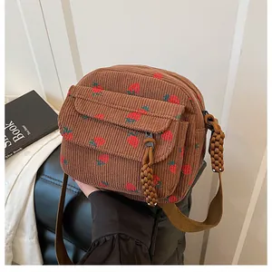 Detail of vintage brown corduroy crossbody bag with strawberry print and rope zipper pull