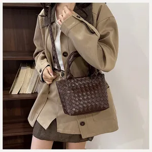 Lifestyle shot of a dark brown woven leather tote bag worn as a shoulder bag