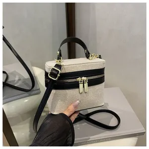 Detailed view of canvas vanity bag with black leather trim and gold metal zippers
