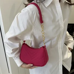 Minimalistische fuchsia V-Stepp-Unterarmtasche mit goldener Kette auf weißem Hemd