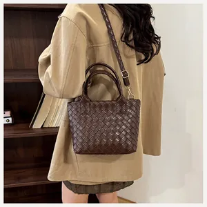 Close-up of a woven dark brown leather bucket bag with an adjustable shoulder strap