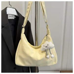 Light yellow PU leather hobo bag with cloud charm detail hanging on metal hanger