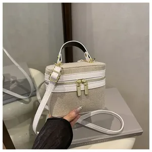 Detail of beige canvas and white leather box bag with gold double zippers and handles