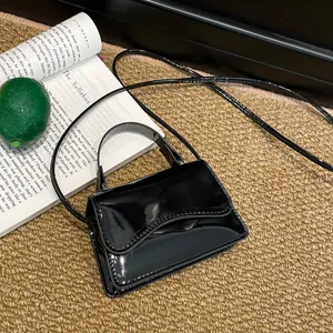 Mini sac à bandoulière en cuir verni noir avec rabat ondulé sur fond texturé élégant