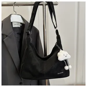 Detail of matte black tote bag featuring Tidal Dryness logo and white cloud plush charm