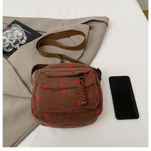 Close-up of brown corduroy crossbody bag with strawberry print and zipper pocket