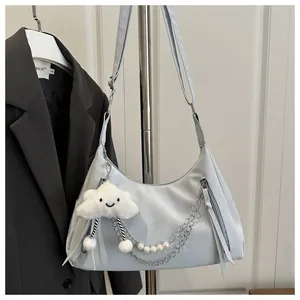 Detail of light blue crescent hobo bag featuring pearl chain and plush cloud charm